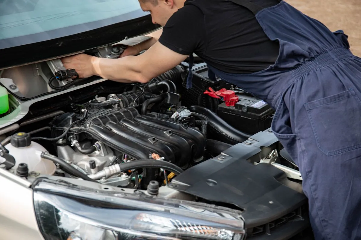 Technician inspecting a car AC system during diagnostics