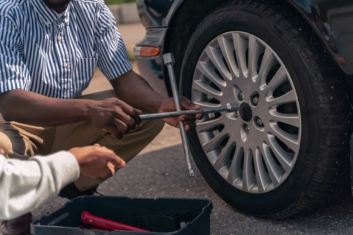 Technician performing wheel alignment service on a sedan