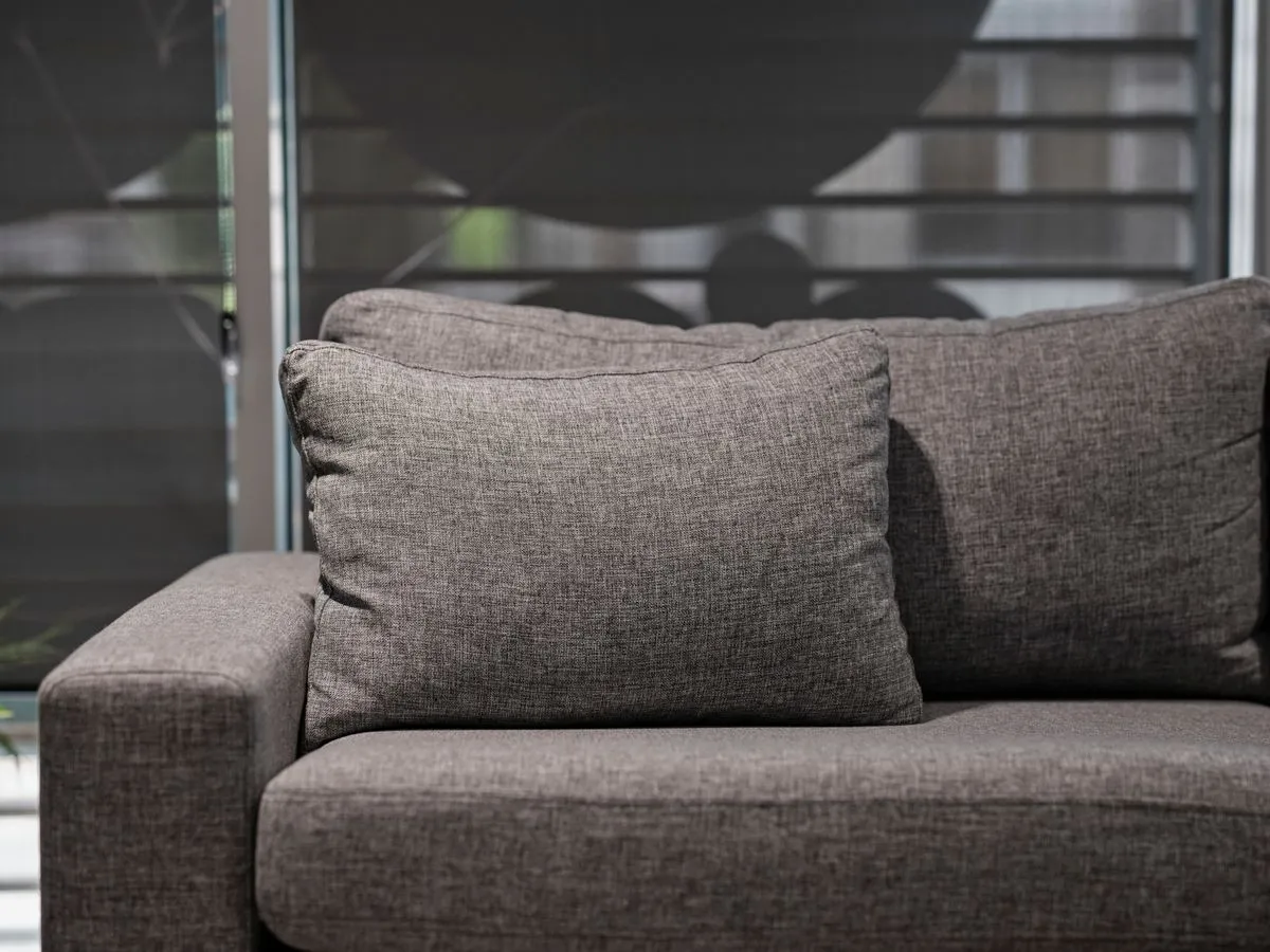 Technician performing upholstery cleaning on a light-colored sofa in a modern living room