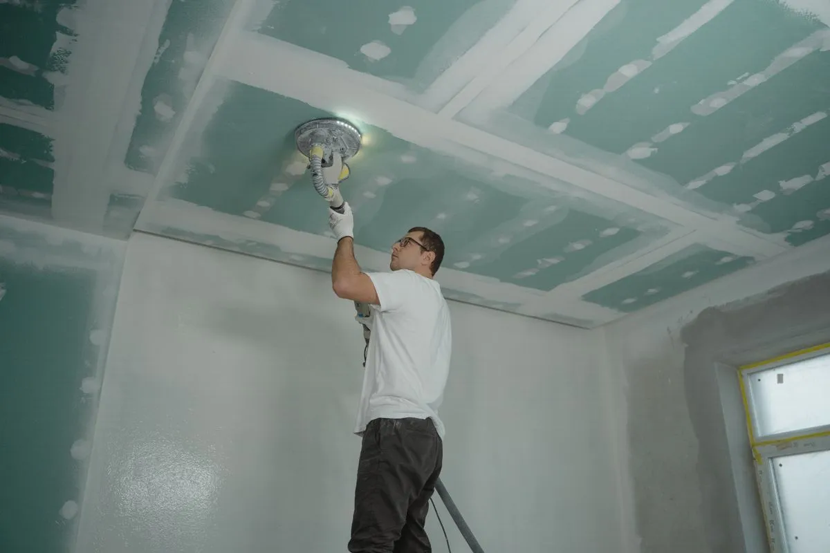 Technician performing ceiling repair in a bright living room
