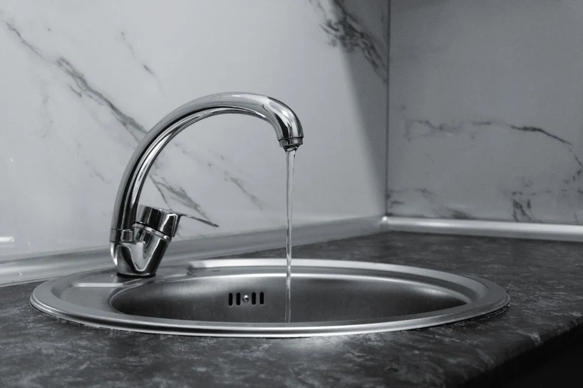 Technician performing drain cleaning service in a residential kitchen