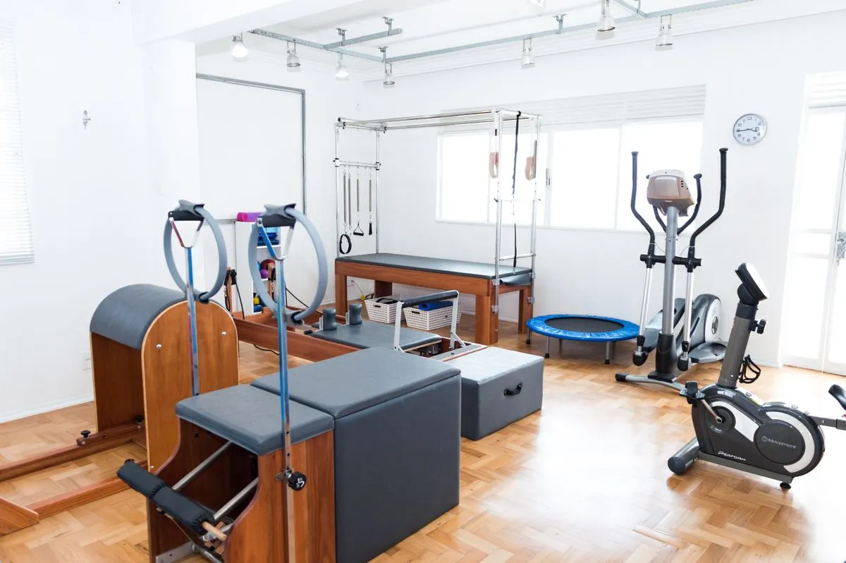 Sala de atendimento da clínica de fisioterapia com maca e equipamentos de reabilitação