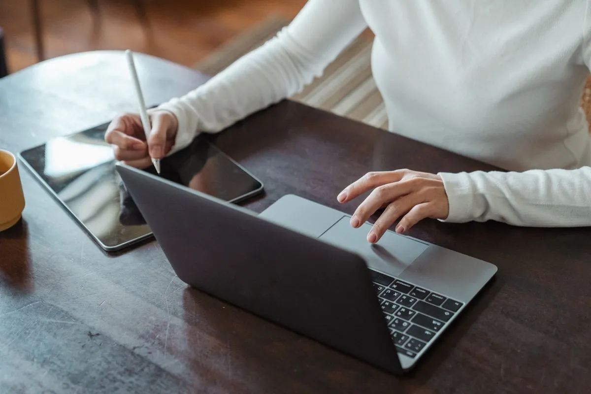 Pessoa estudando em notebook com café e caderno sobre a mesa