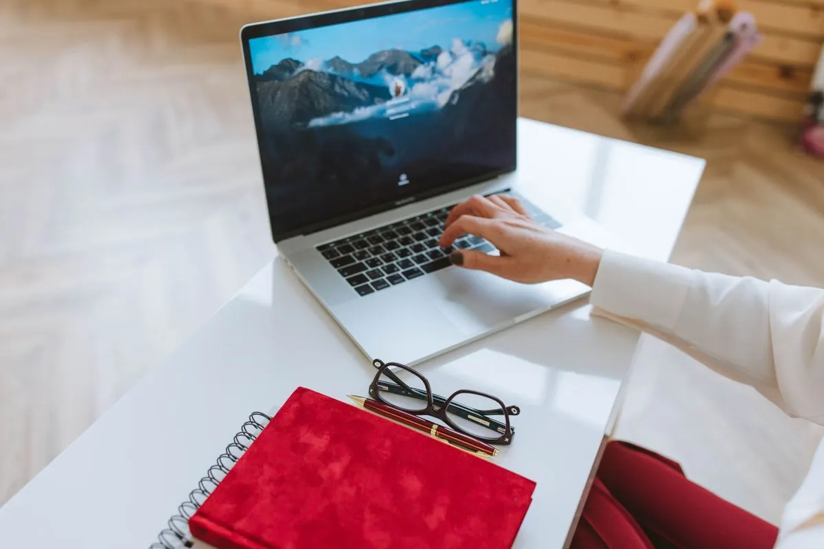 Pessoa estudando em notebook com anotações ao lado em um ambiente de home office